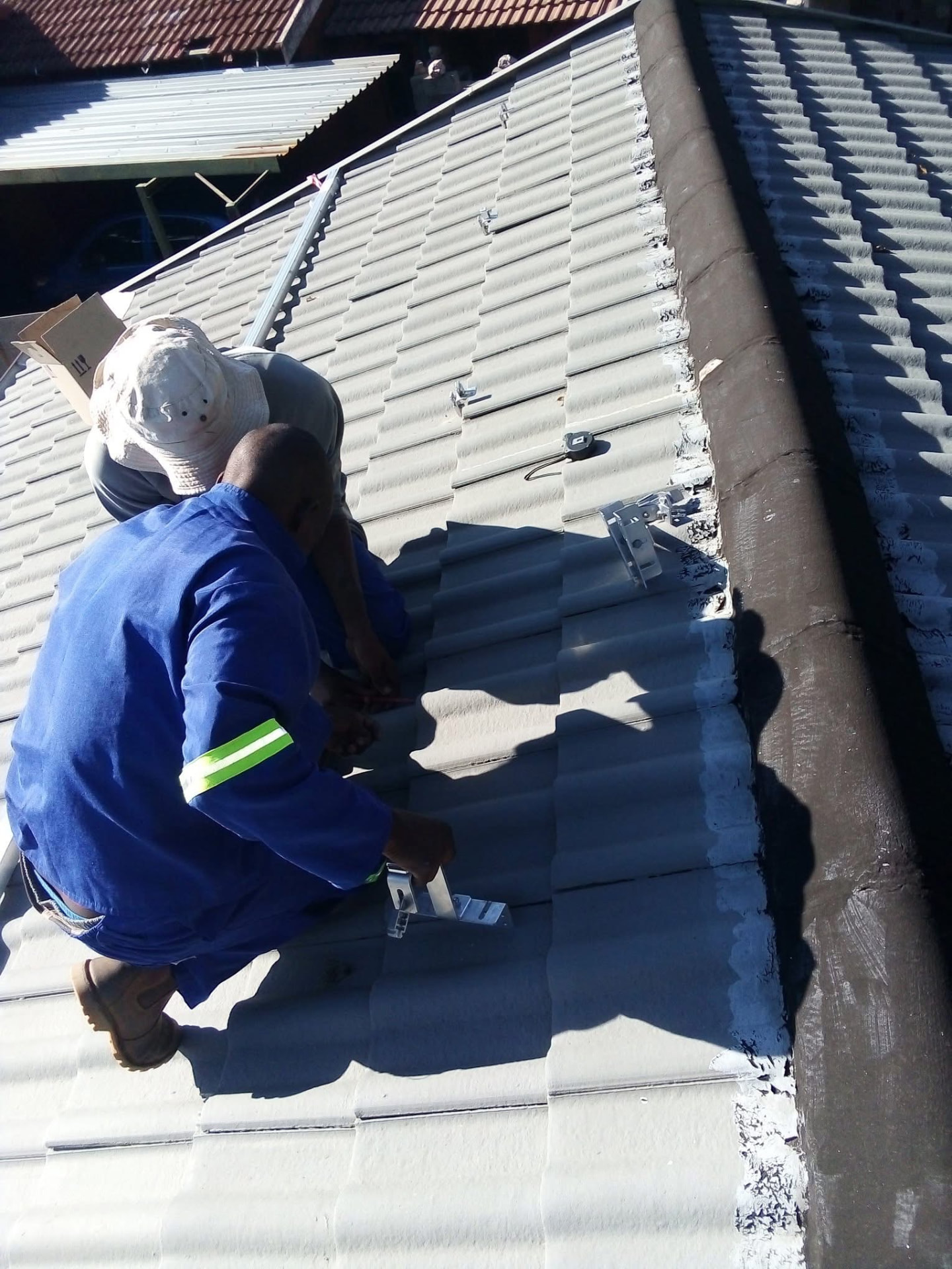 NEAT technician fixing solar mounting hardware to a corrugated commercial roof
