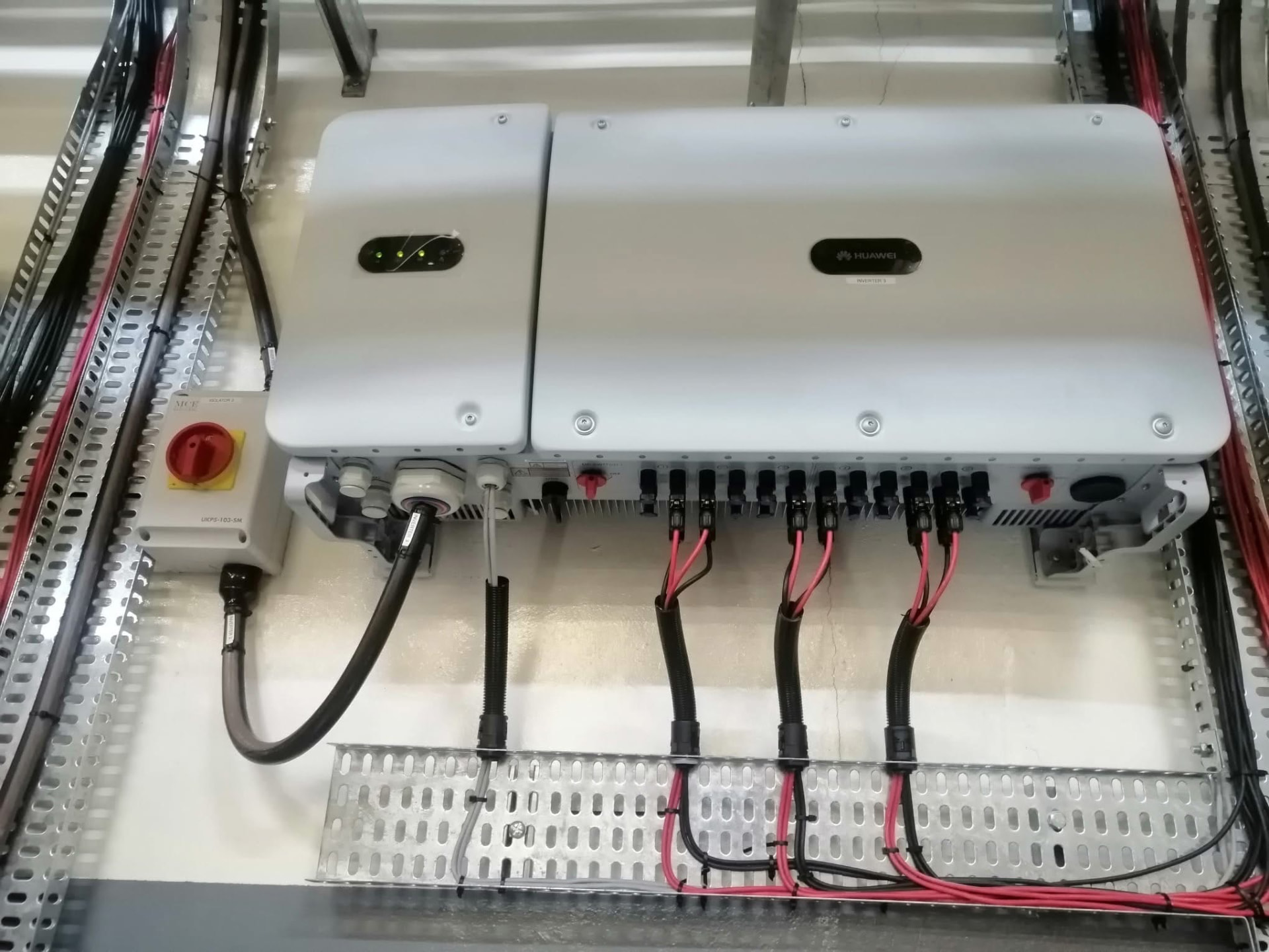 Commissioned inverters with labelled DC strings on galvanised cable tray